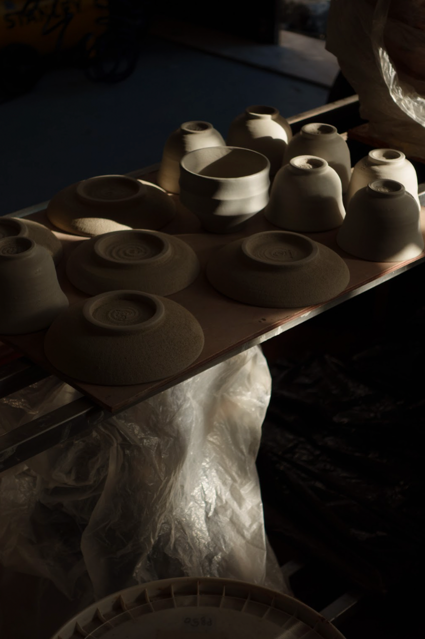 Row of ceramic bowls on a wooden board with a dark background