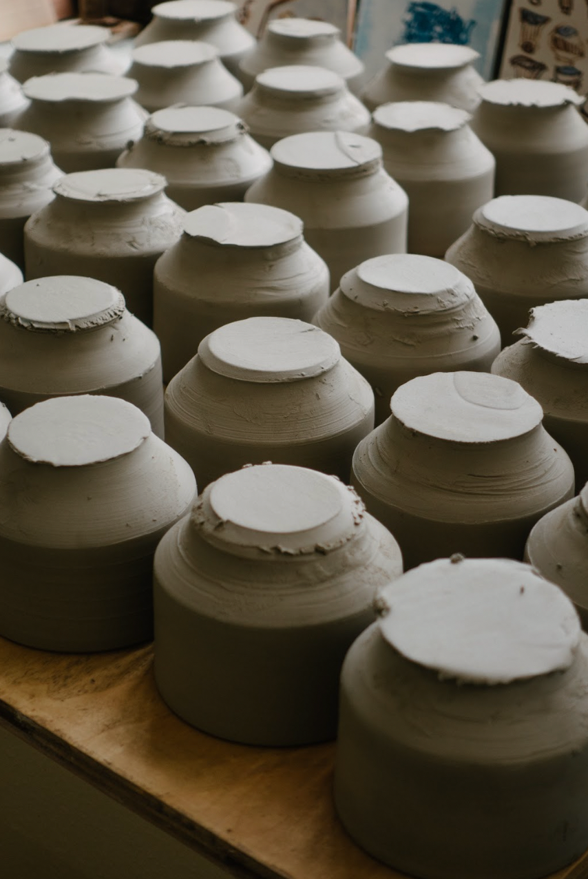 Row of ceramic pots with lids on a wooden surface