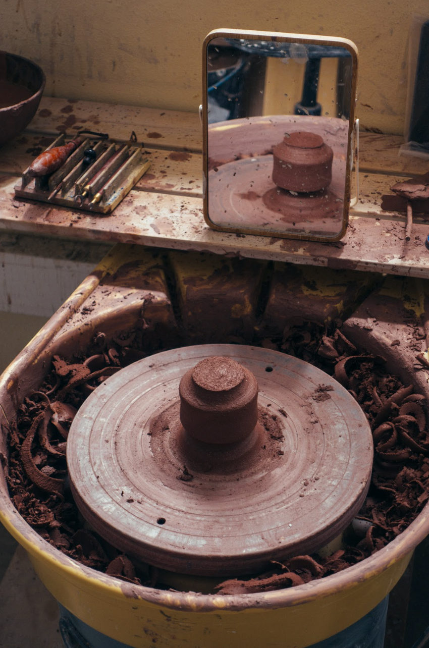 Pottery wheel with clay pot on a workbench in a workshop setting