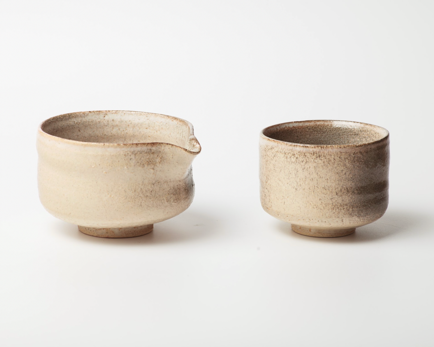 Two ceramic cups with a small spout on a white background
