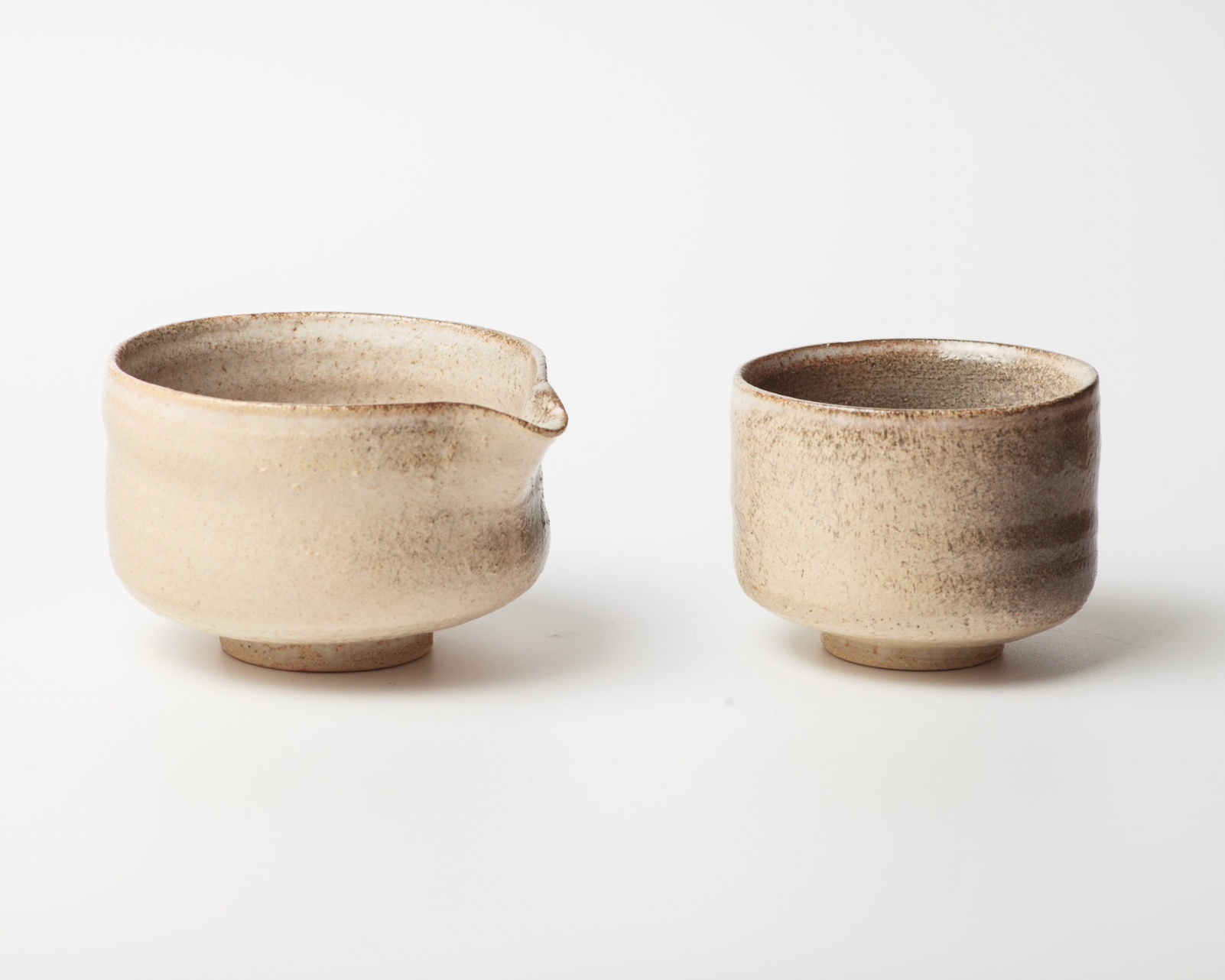Two ceramic cups with a small spout on a white background