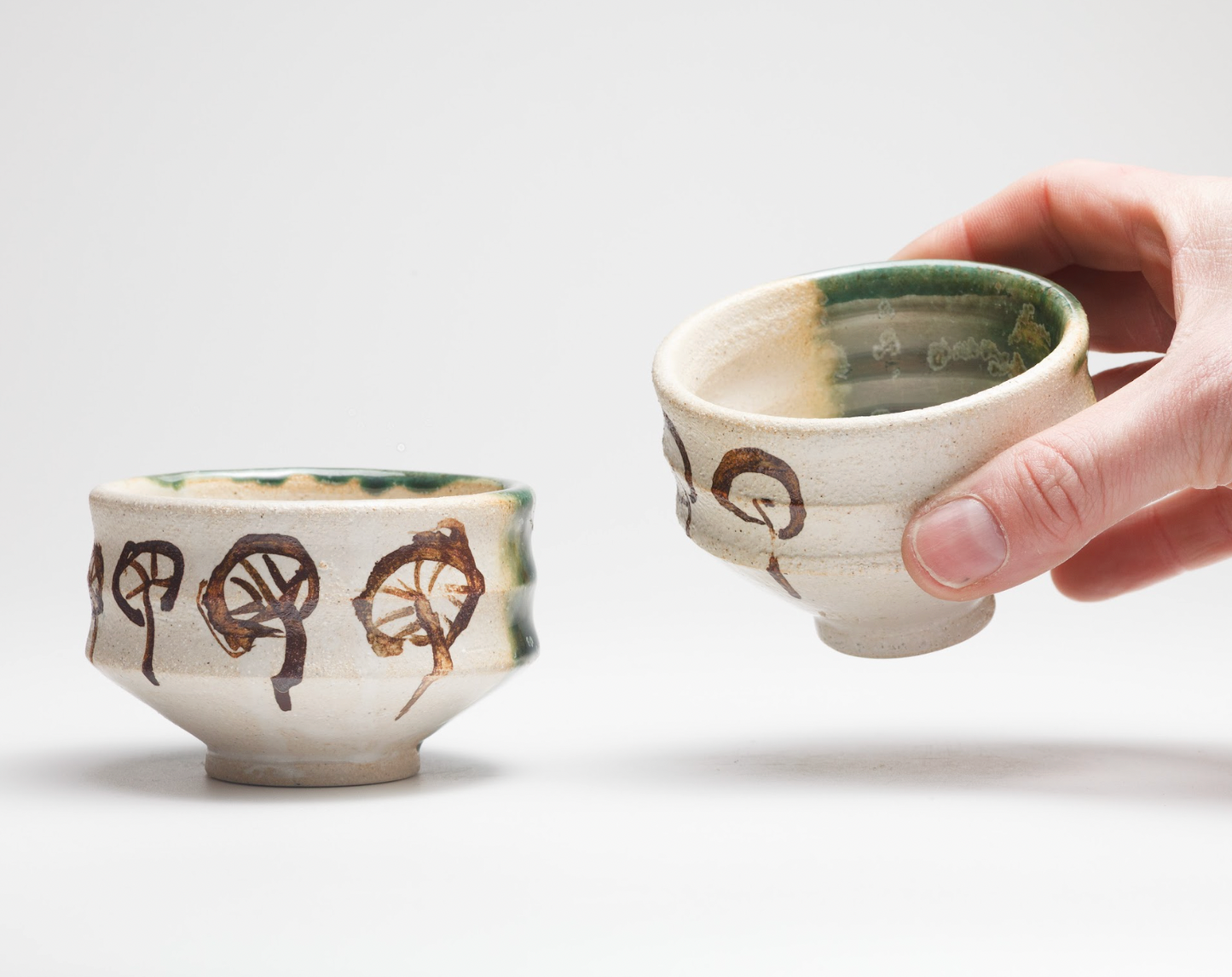 Two ceramic cups with decorative patterns on a light background