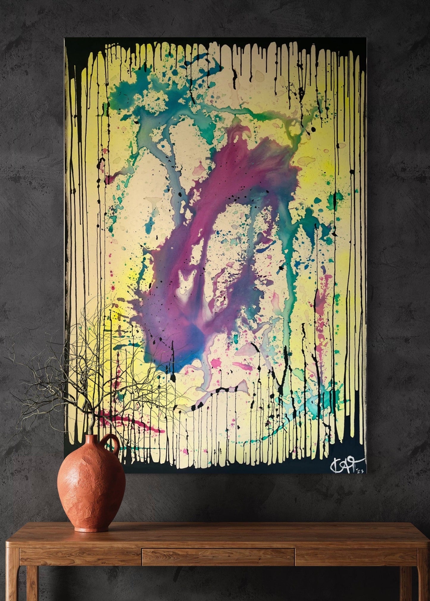 Abstract painting with splashes of color on a dark wall above a wooden table with a vase.