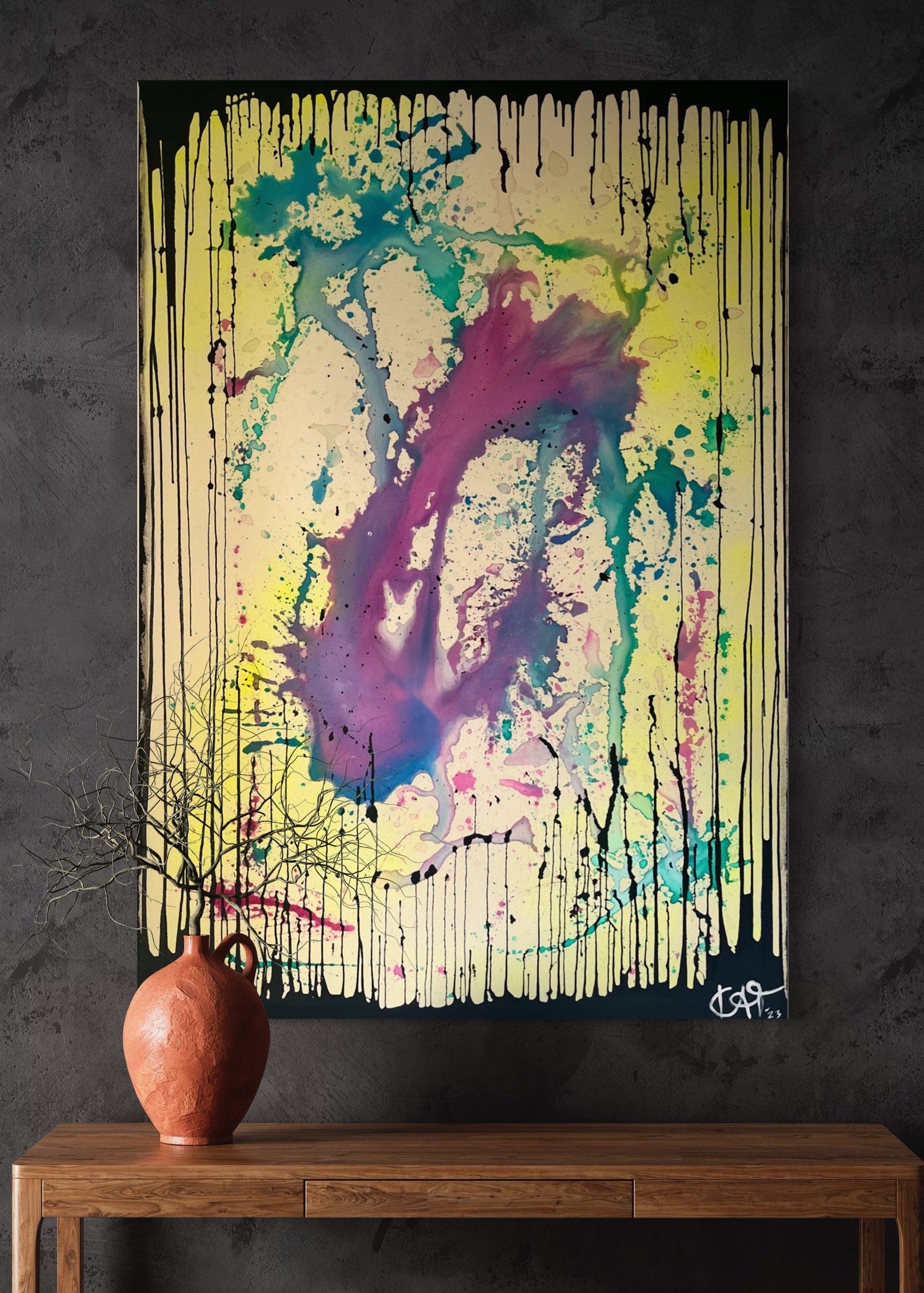 Abstract painting with splashes of color on a dark wall above a wooden table with a vase.