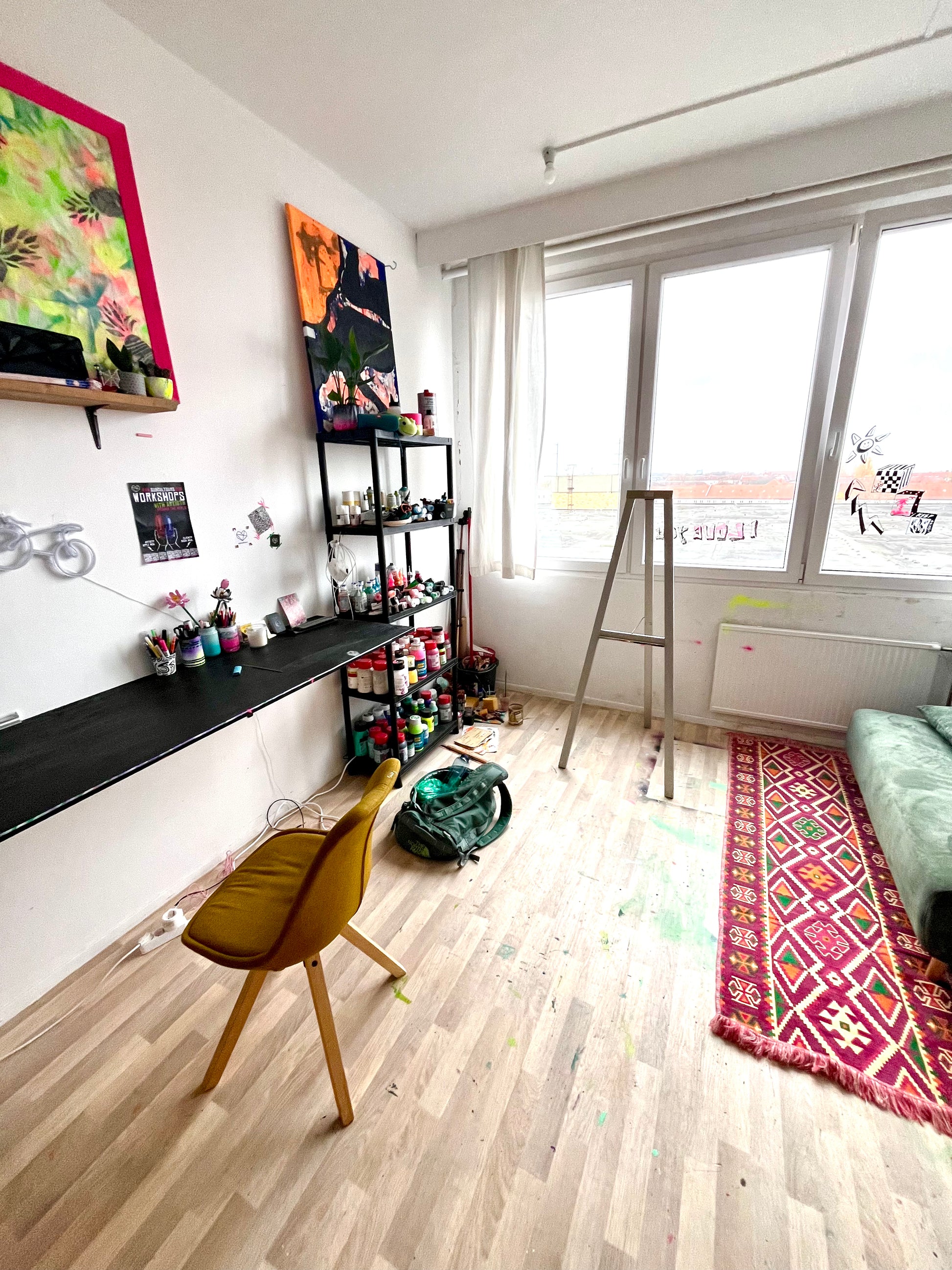 Modern room with a desk, chair, and colorful artwork on a white wall.