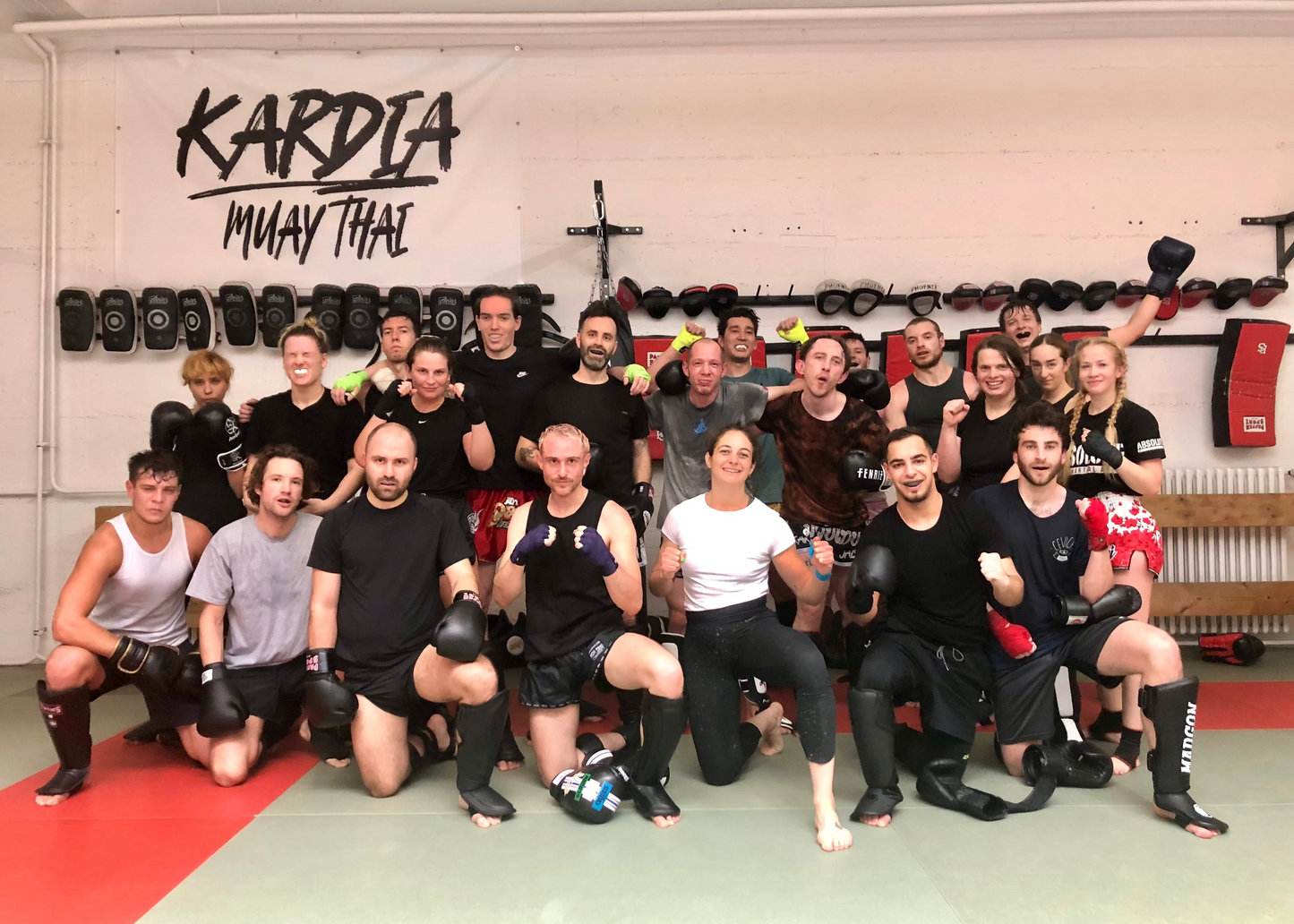 Group of people posing for a photo in a Muay Thai gym with 'Kardia Muay Thai' branding.