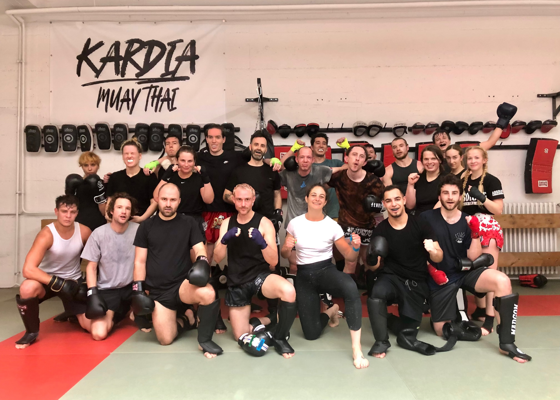 Group of people posing for a photo in a Muay Thai gym with 'Kardia Muay Thai' branding.