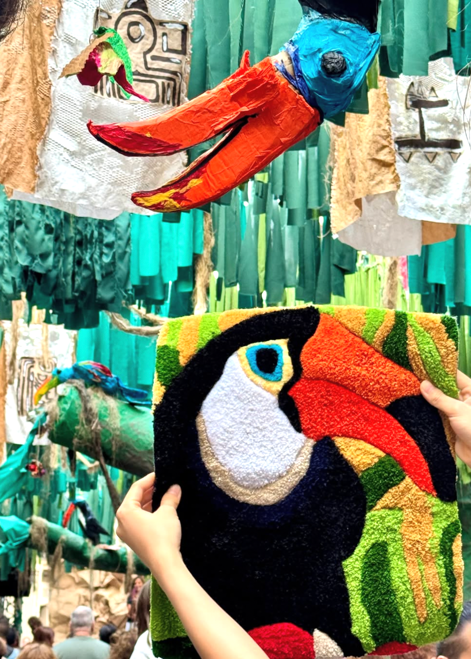 Handmade toucan plush toy held by a person with a colorful background