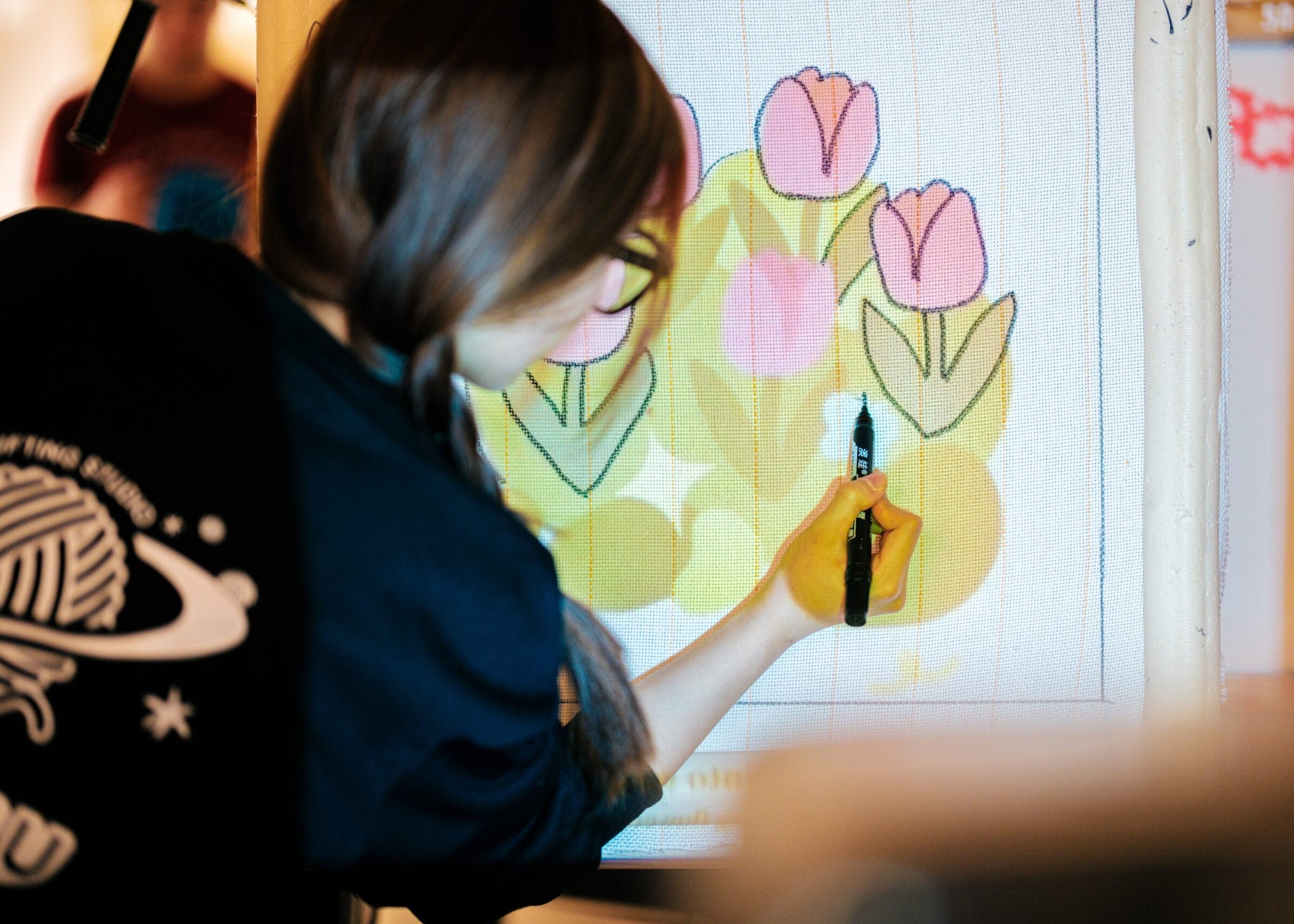 Person drawing a floral design on a digital tablet with a stylus.