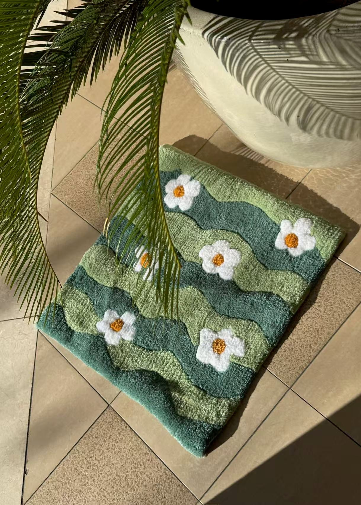 Green rug with white floral patterns on a tiled floor