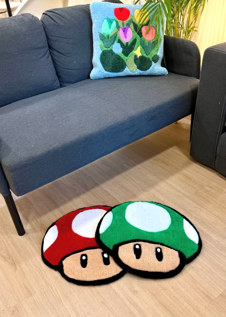 Two mushroom-shaped rugs on a wooden floor in front of a gray sofa with a colorful pillow.