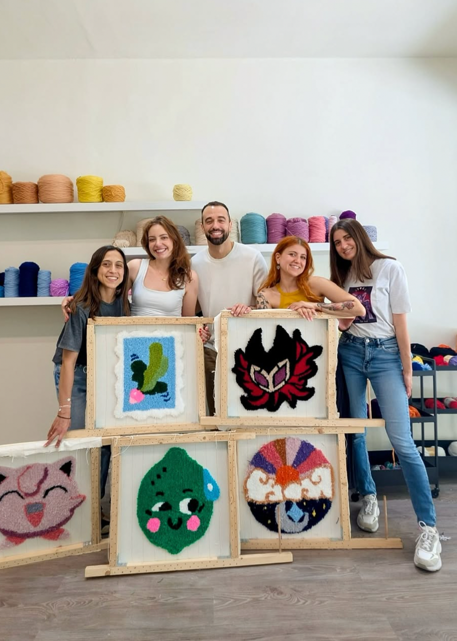 Group of people posing with yarn art pieces in a workshop setting