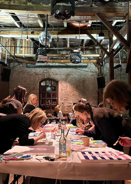 Group of people sitting around a table in a rustic indoor setting, a workshop and studio inside a club in Berlin