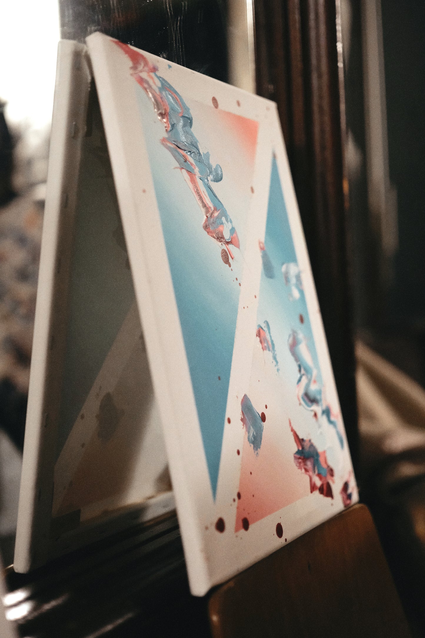 Colorful abstract painting leaning against a reflective surface