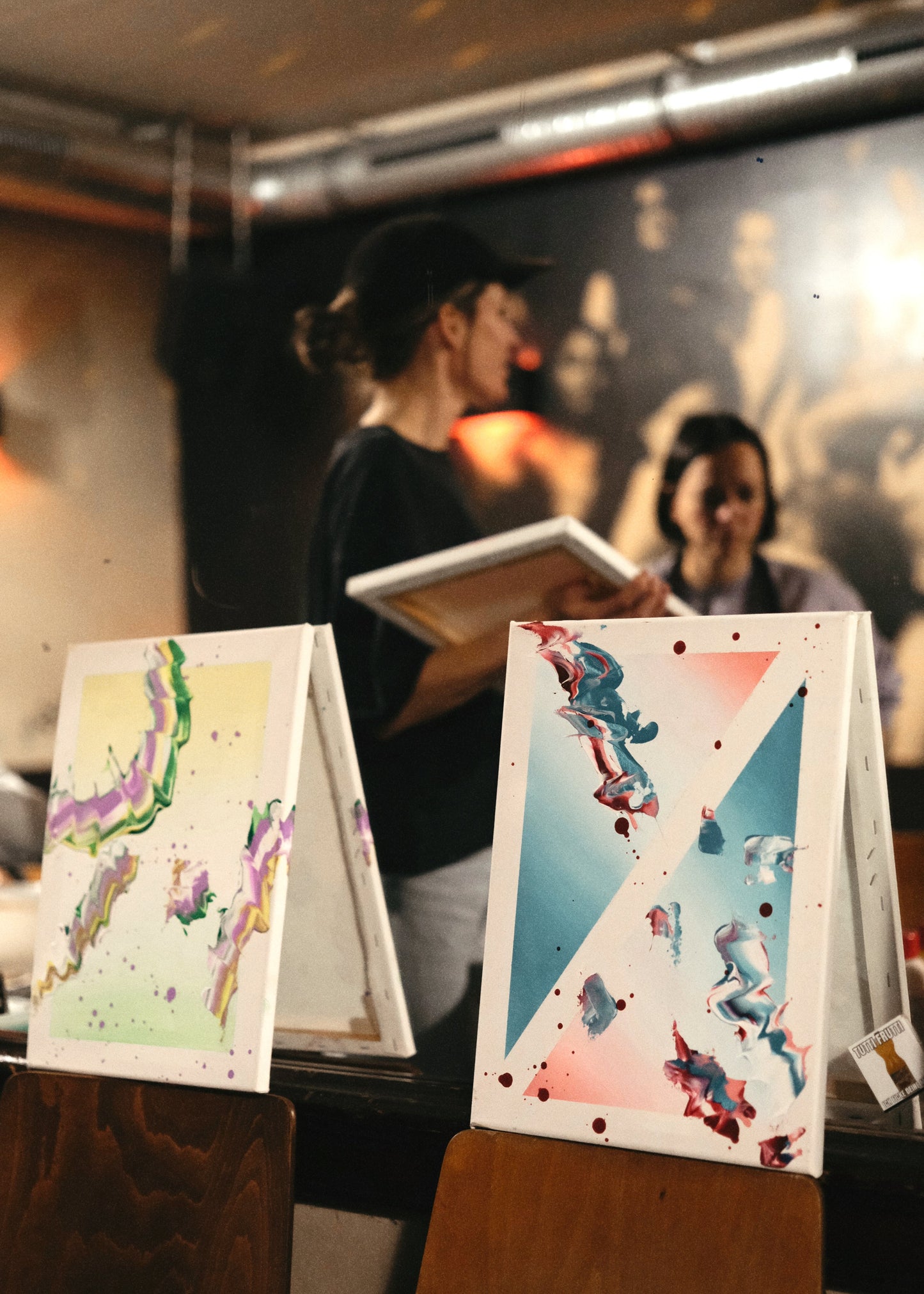 Colorful abstract artworks on stands with people in the background
