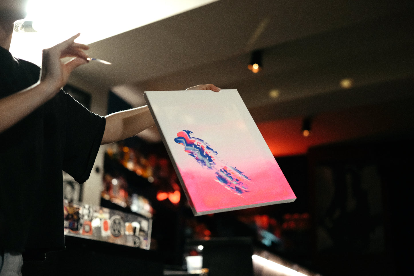 Person holding a tablet with a colorful display in a dimly lit room