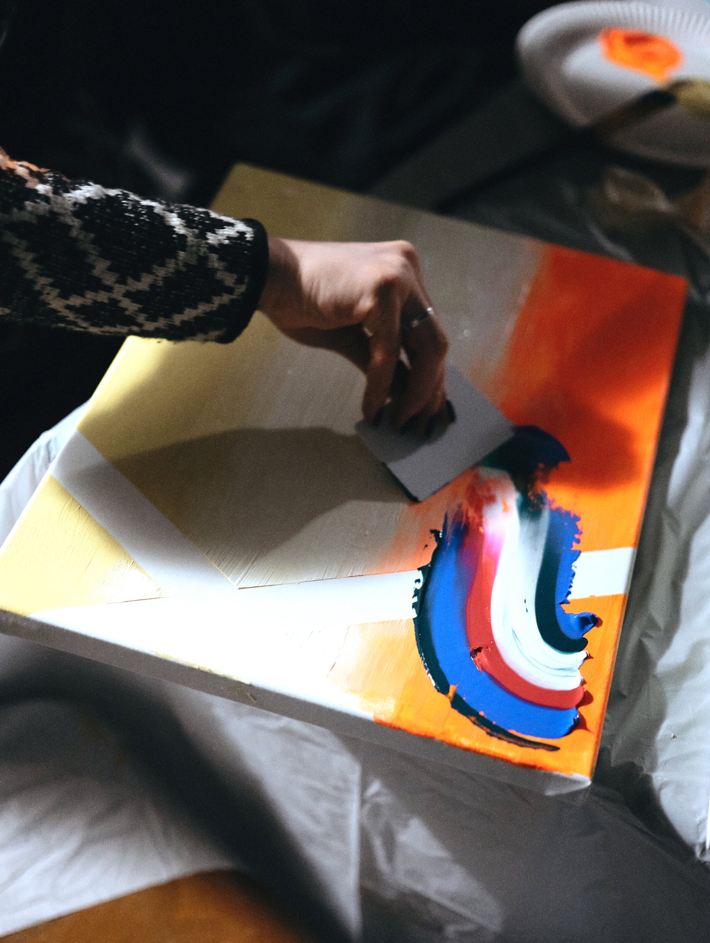 Person cutting a piece of paper with colorful abstract design on a table.