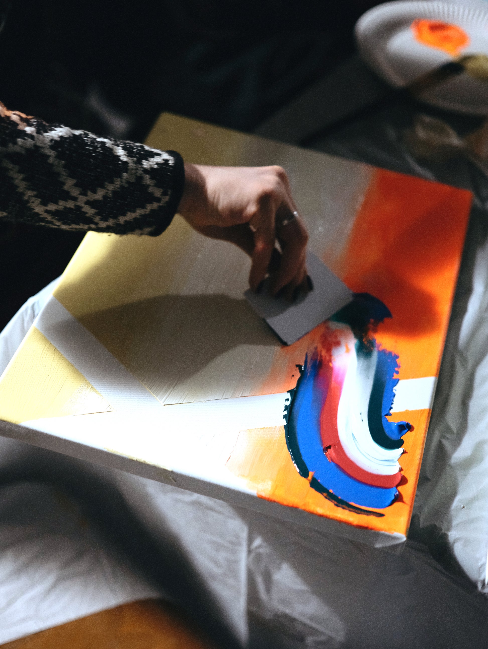 Person cutting a piece of paper with colorful abstract design on a table.