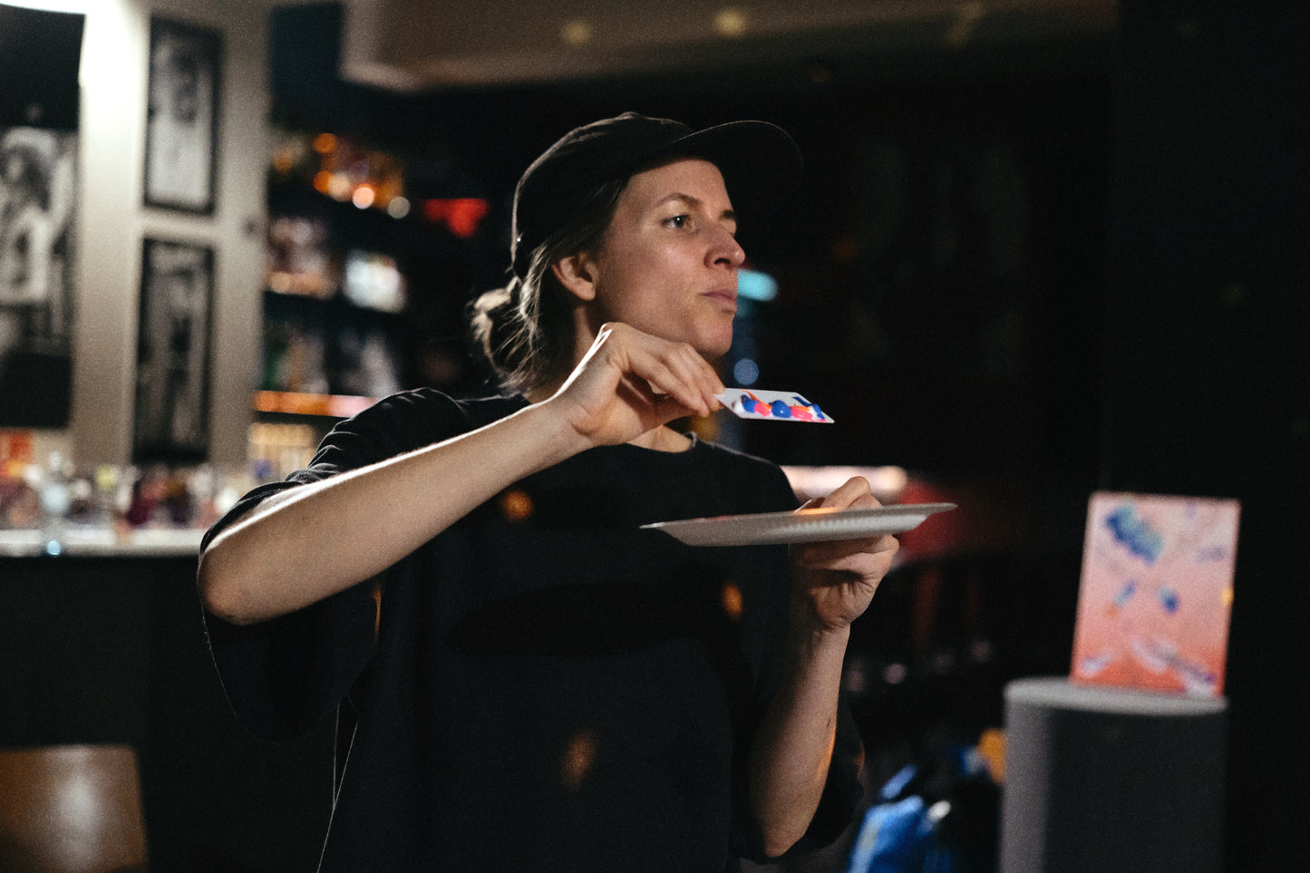 Person holding a plate with a blurred bar or restaurant setting in the background