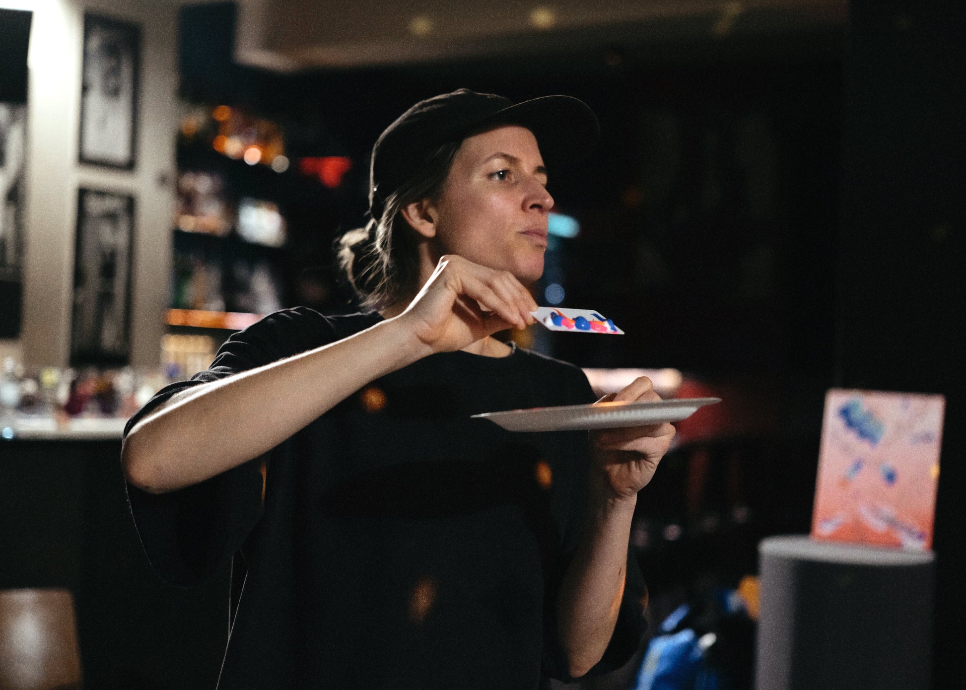 Person holding a plate with a blurred bar or restaurant setting in the background