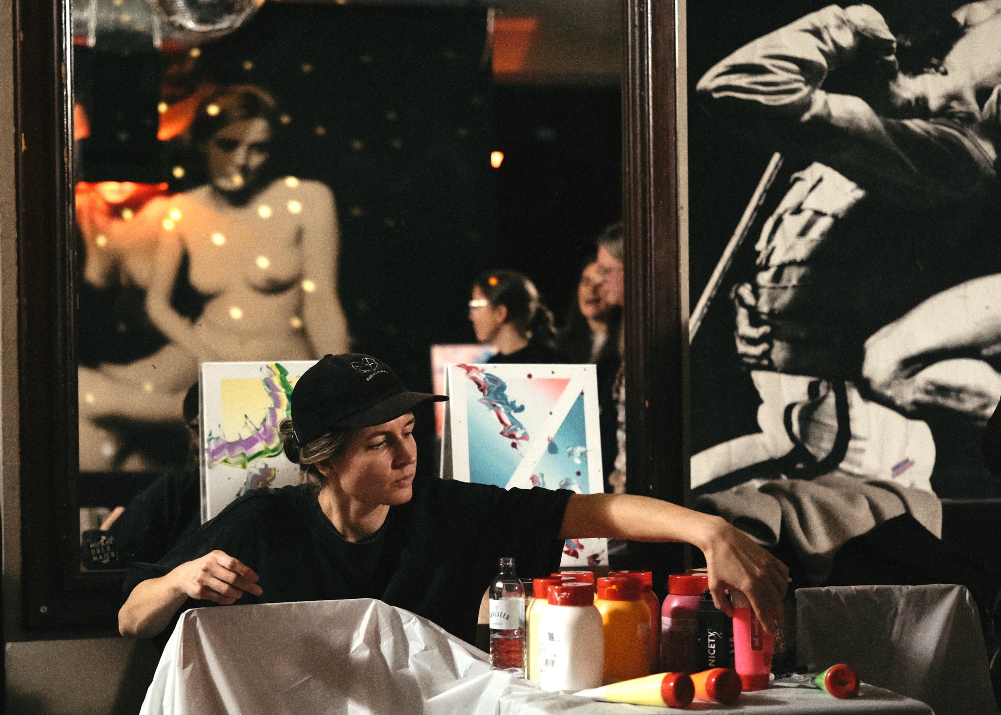Person sitting at a table with drinks and artwork in the background