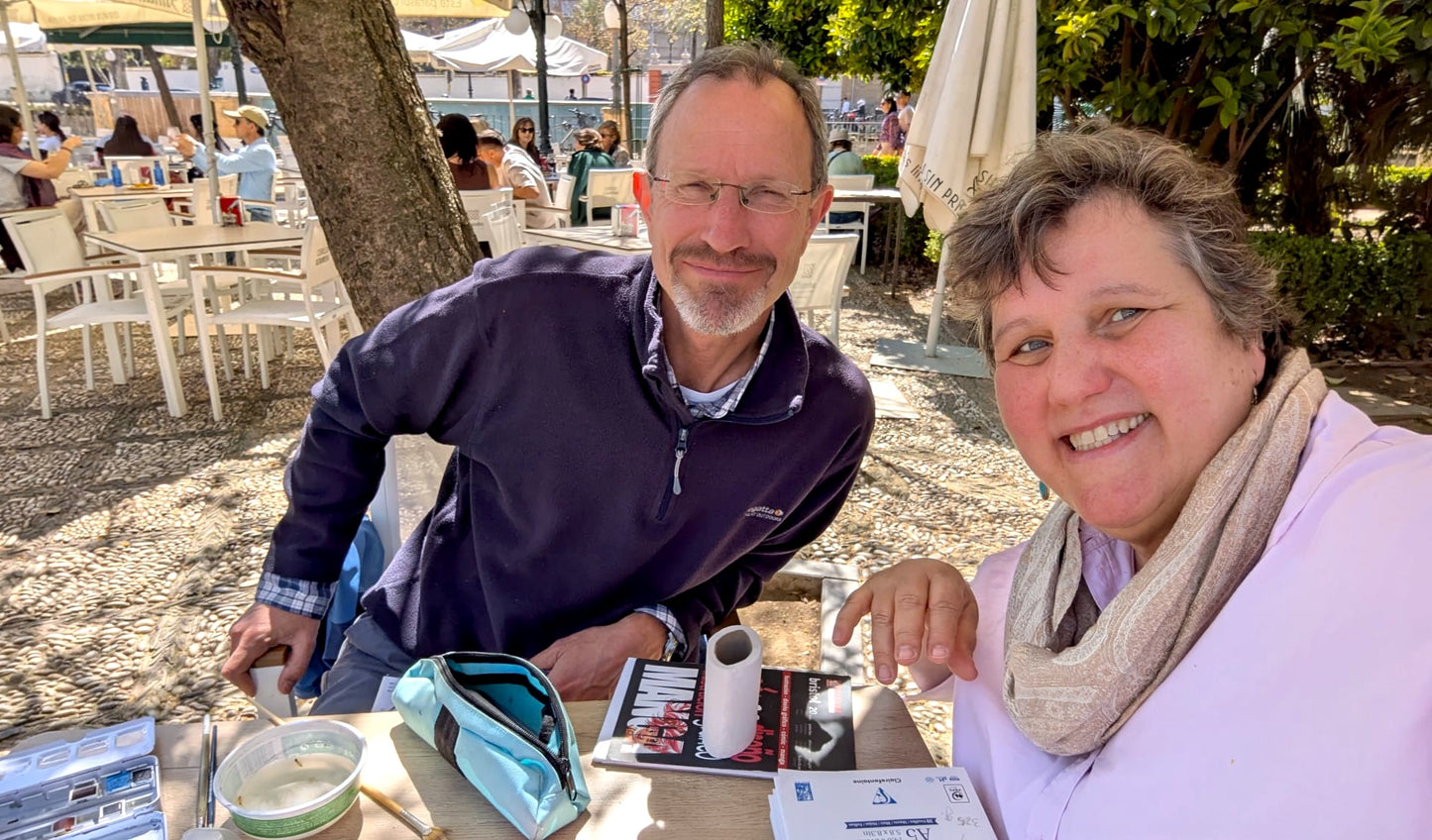 Two people sitting at an outdoor table with a scenic background
