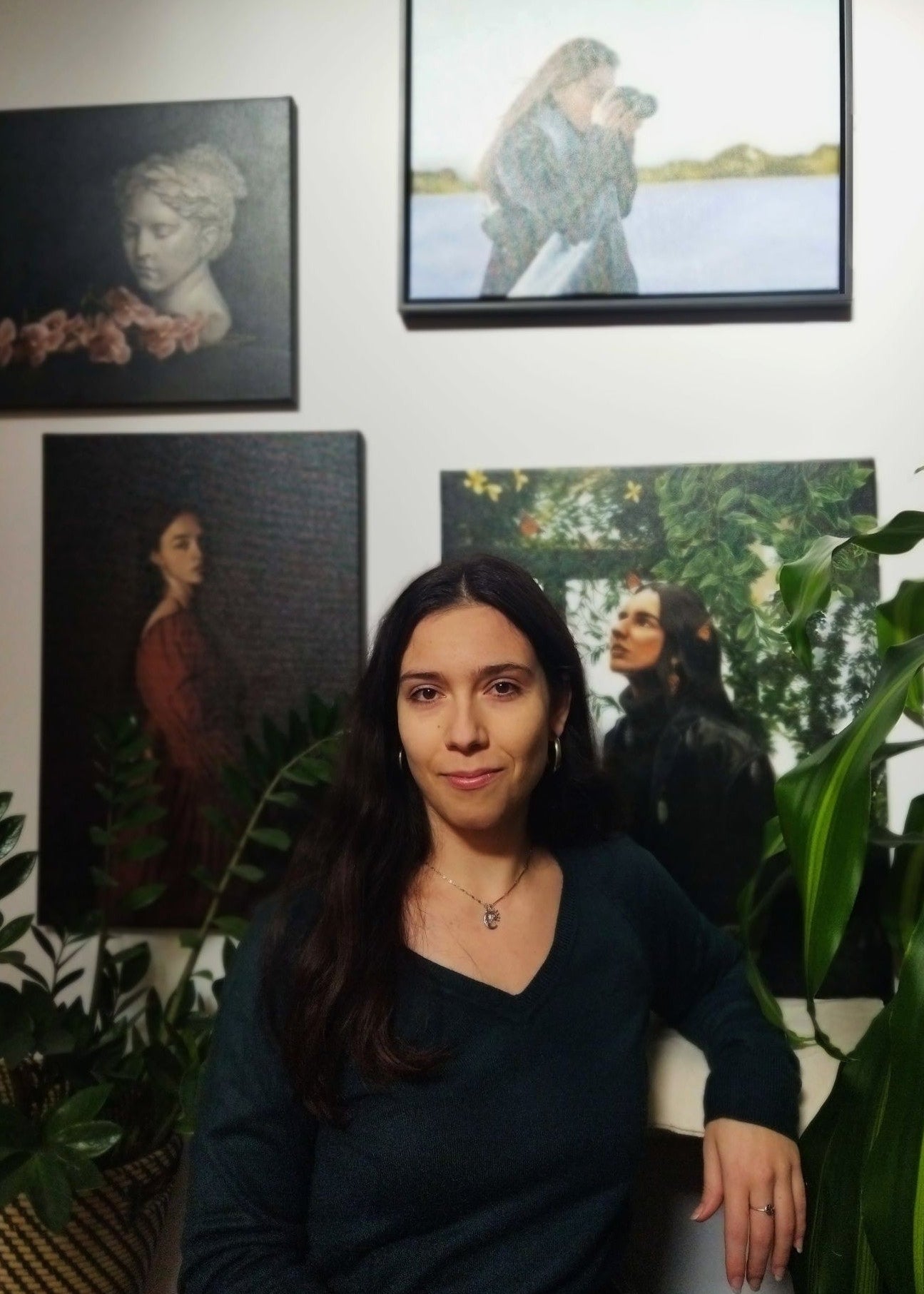 Woman sitting in a room with artistic wall decorations and plants.