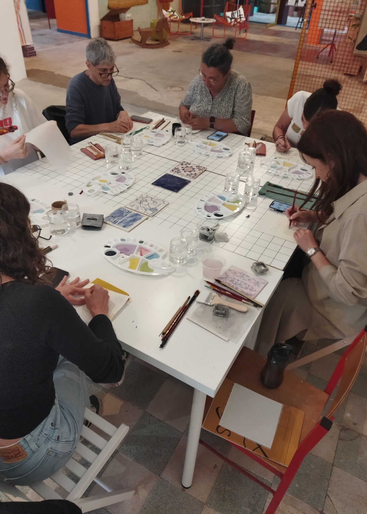 Group of people sitting around a table with art supplies in a casual setting