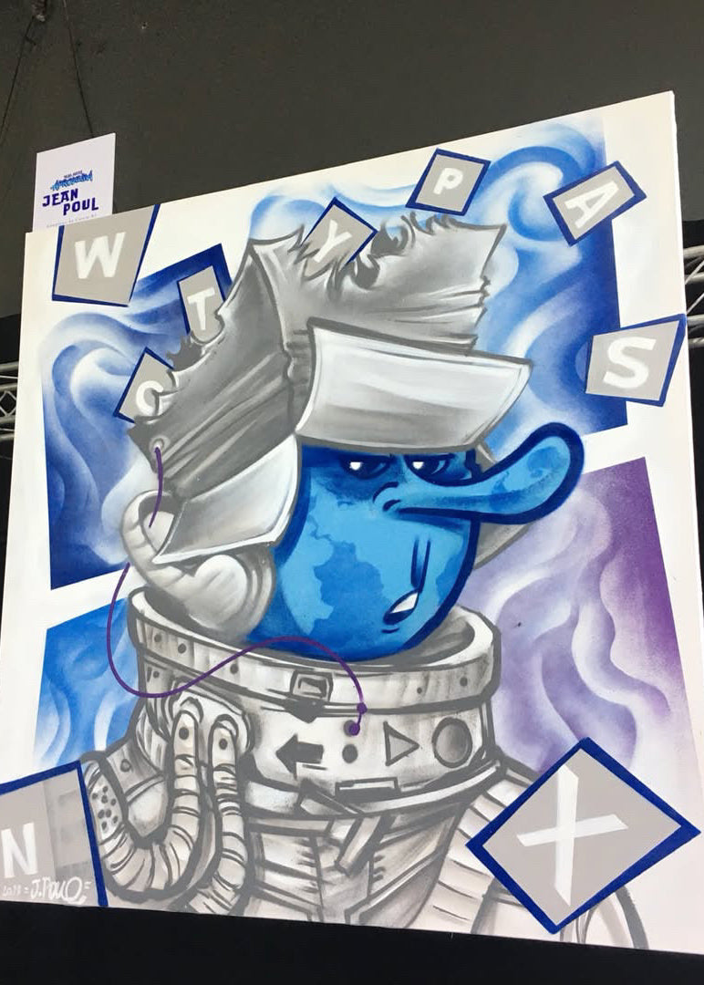 A large square art print or poster featuring a stylized blue cartoon character in a silver space suit, surrounded by abstract blue and purple shapes and letter tiles, photographed hanging against a dark exhibition space with truss bars visible.