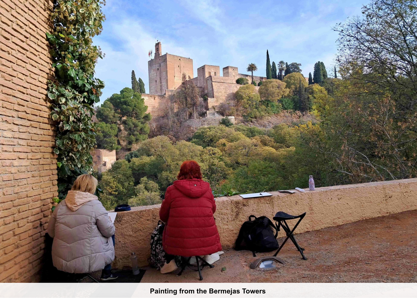 Two people sitting on a wall with a castle in the background
