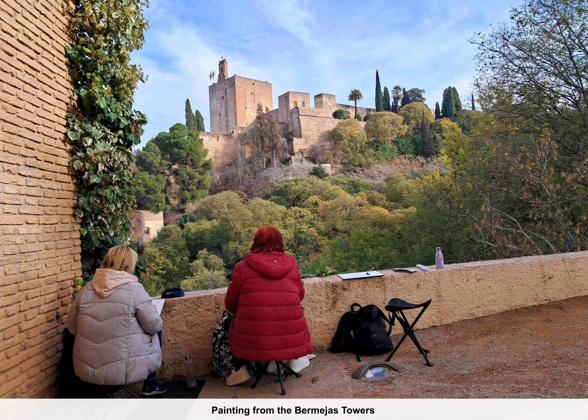 Two people sitting on a wall with a castle in the background