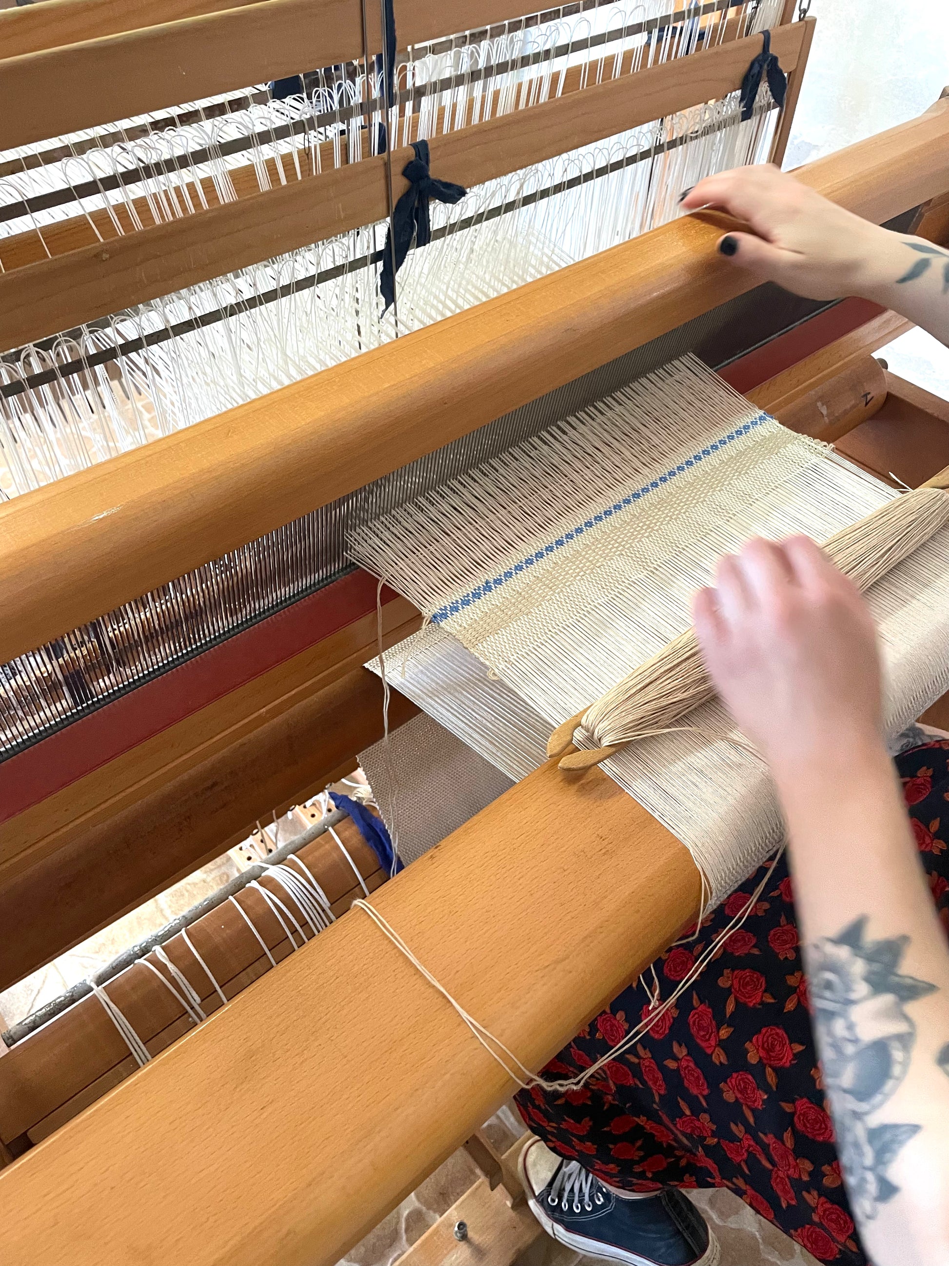 Person weaving on a loom with fabric and threads.