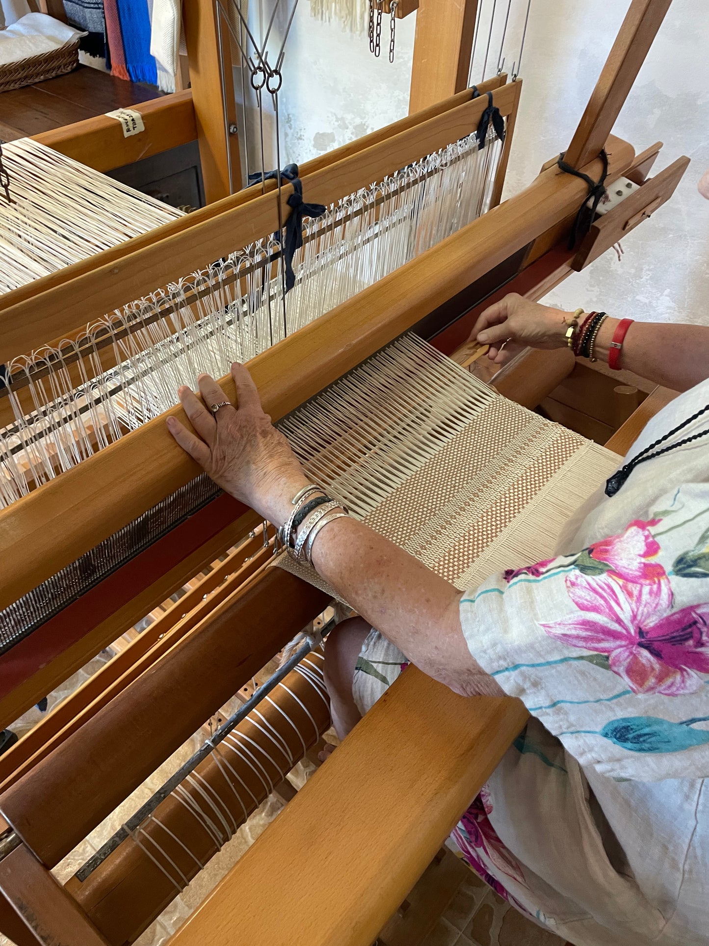 Person weaving on a wooden loom with colorful fabric.