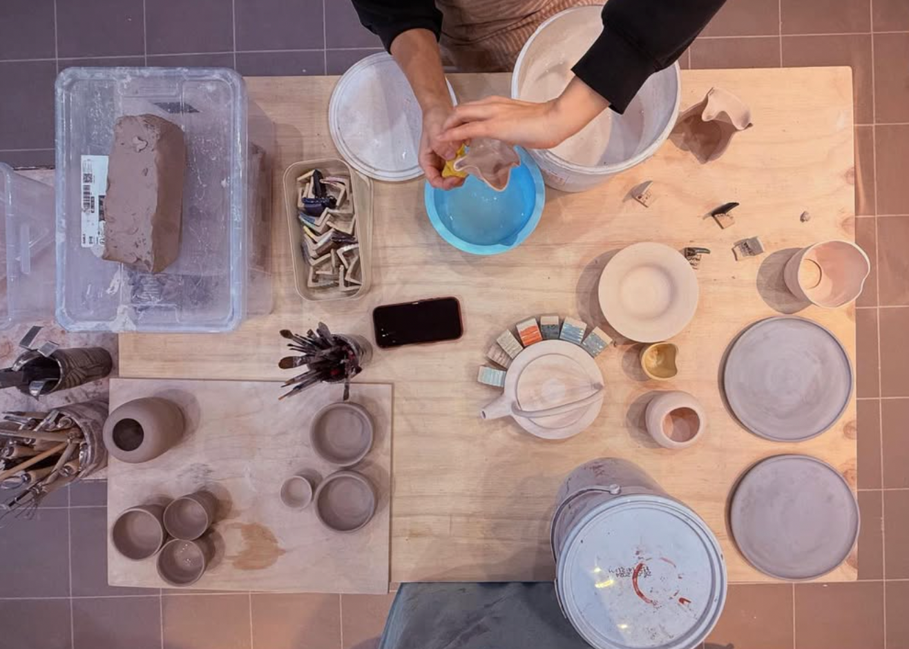Person working with clay on a pottery wheel in a studio setting