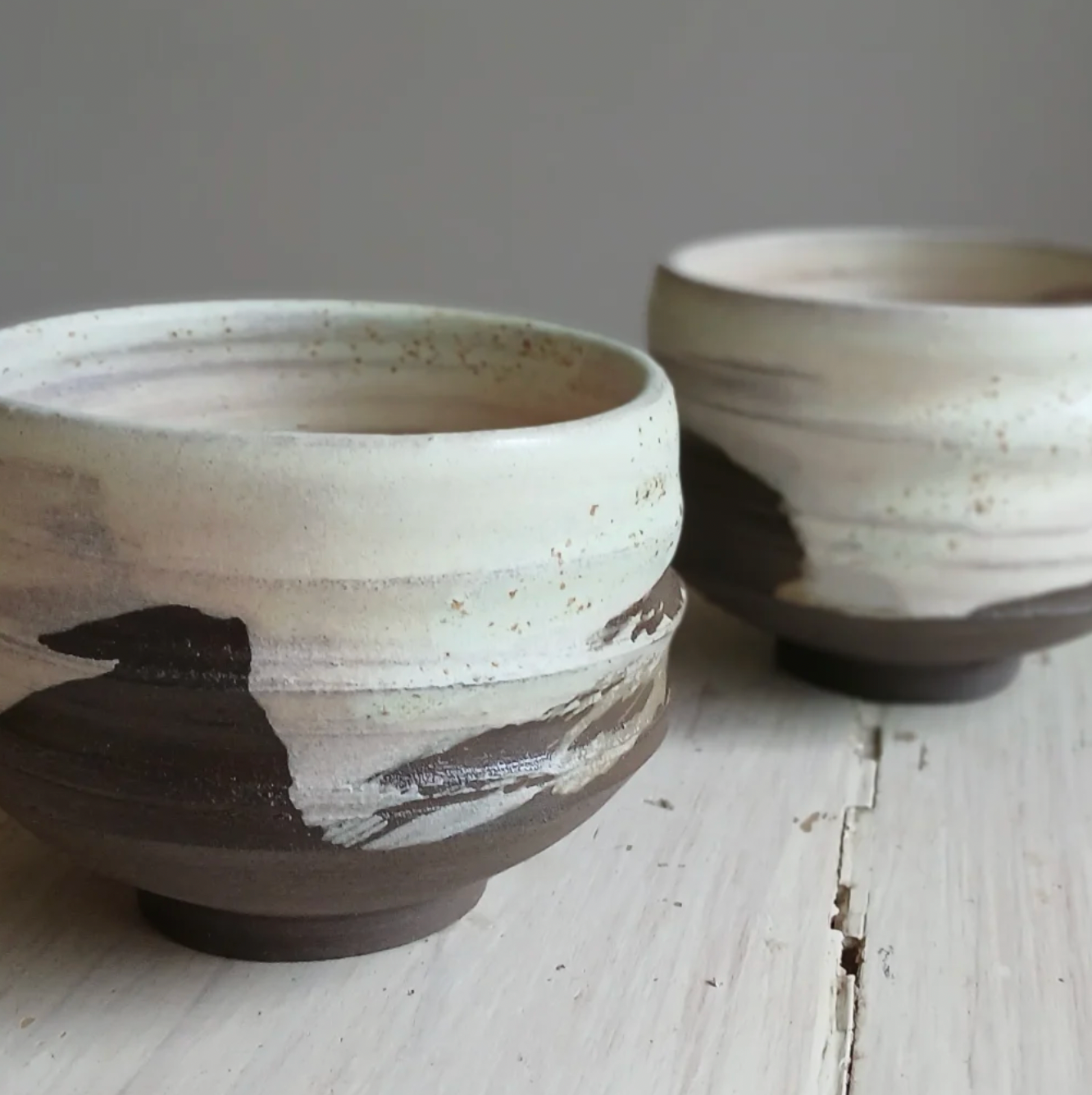 Two ceramic bowls on a wooden surface with a neutral background