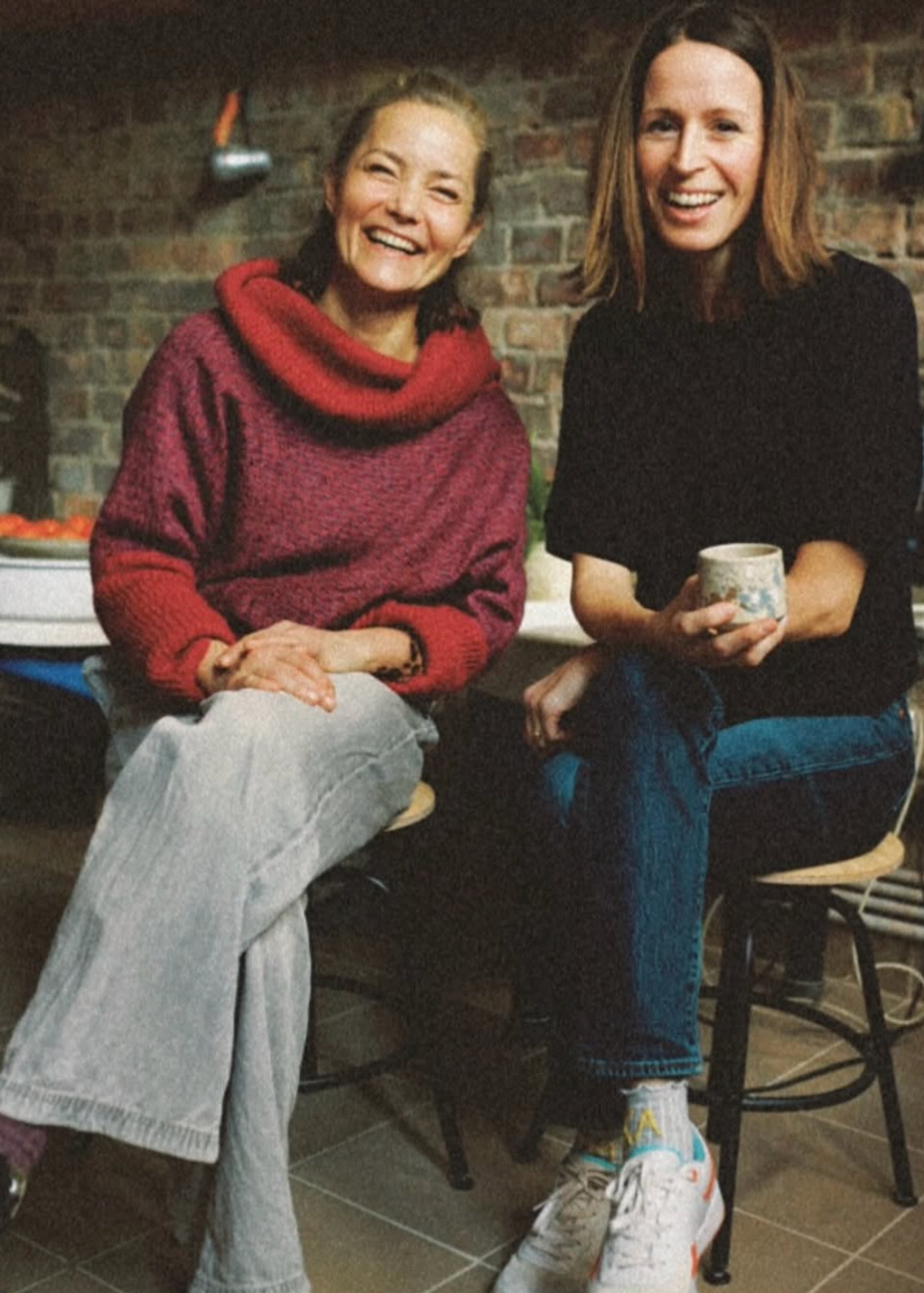 Two women sitting together in a casual setting, smiling.