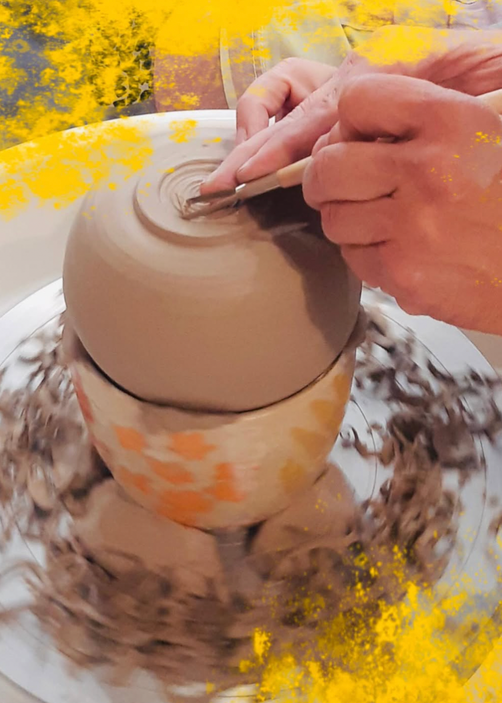 Person working on a ceramic pot with a yellow floral pattern, surrounded by yellow flowers.