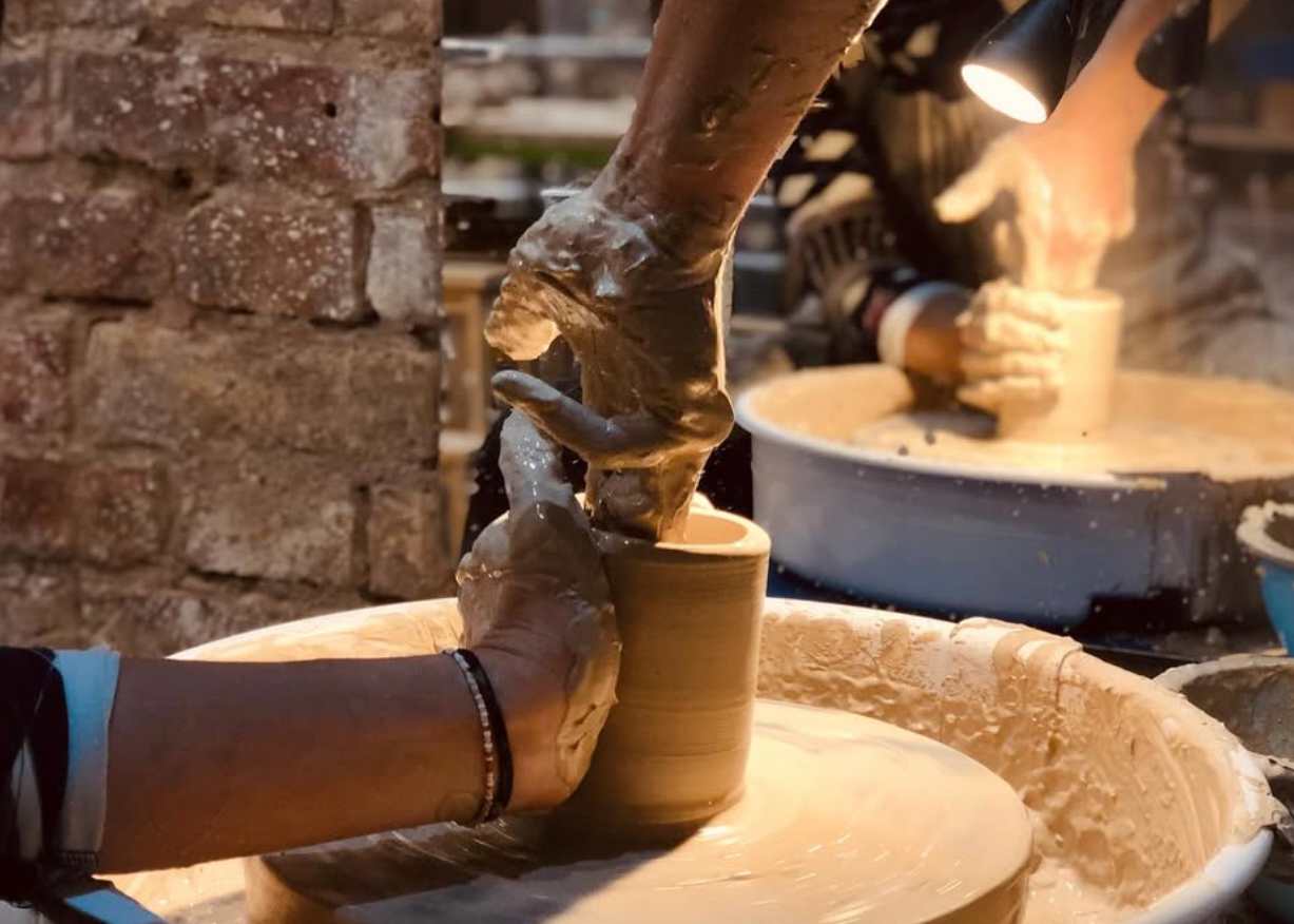 Person working with clay on a pottery wheel in a workshop setting.
