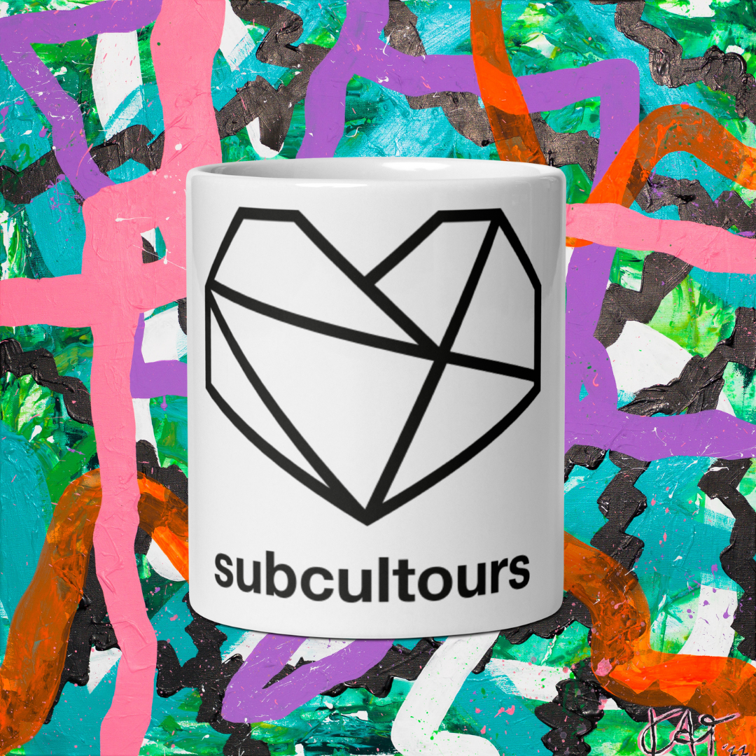 White mug with geometric heart design and 'subcultours' text on a colorful abstract background
