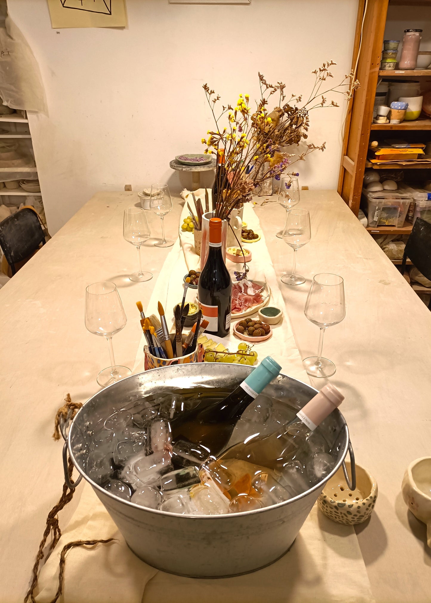 Table with wine bottles, glasses, and a bucket of ice in a casual setting.