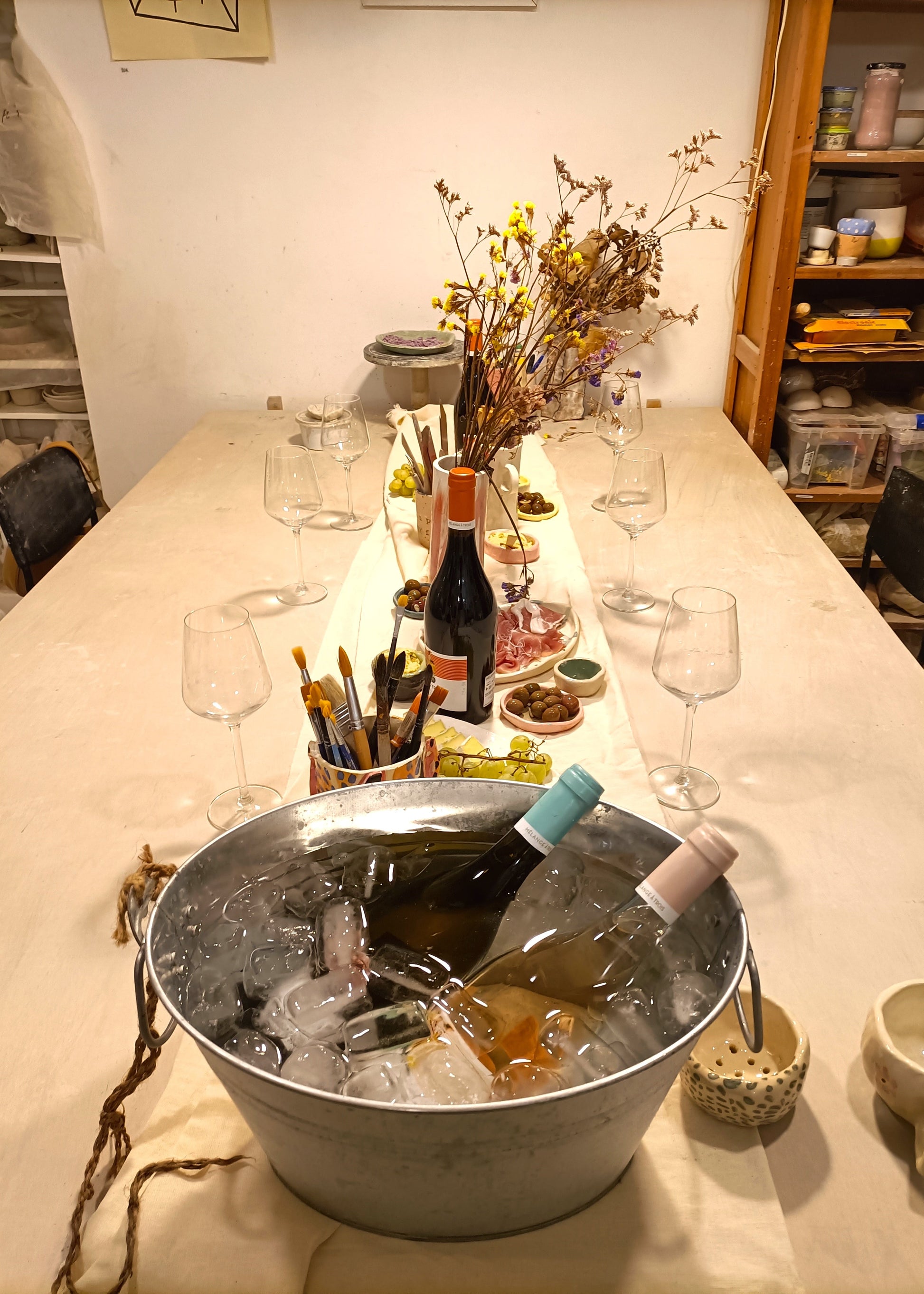 Table with wine bottles, glasses, and a bucket of ice in a casual setting.