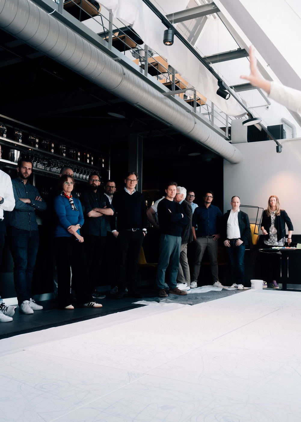 Group of people standing in a modern indoor setting with high ceilings.