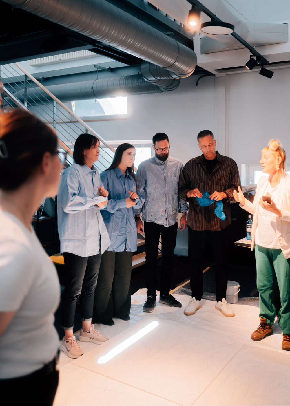Group of people standing in a modern office space, engaged in a discussion.
