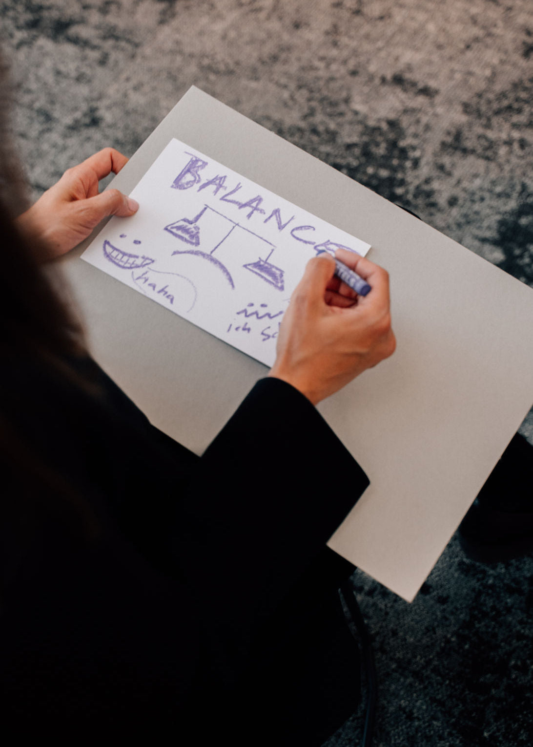 Person drawing a balance diagram on a piece of paper with a pen.