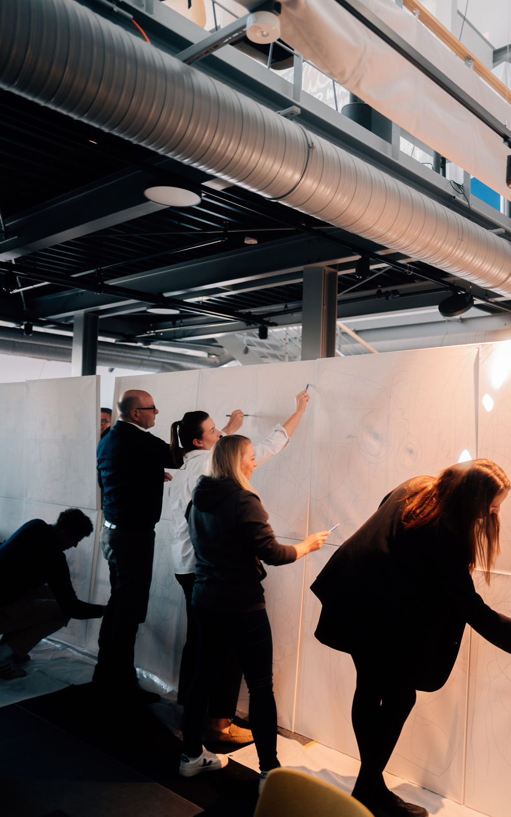 Group of people interacting with a whiteboard in an industrial setting